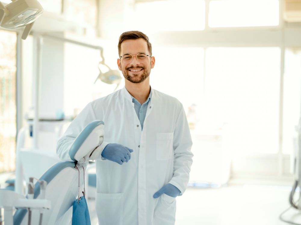Dentista sorrindo em consultório odontológico moderno, representando a profissão e informações sobre quanto ganha um dentista do SUS no Brasil.